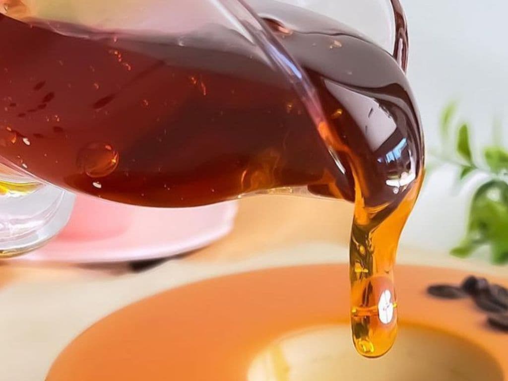 Calda de caramelo dourada sendo despejada sobre o Pudim Perfeito